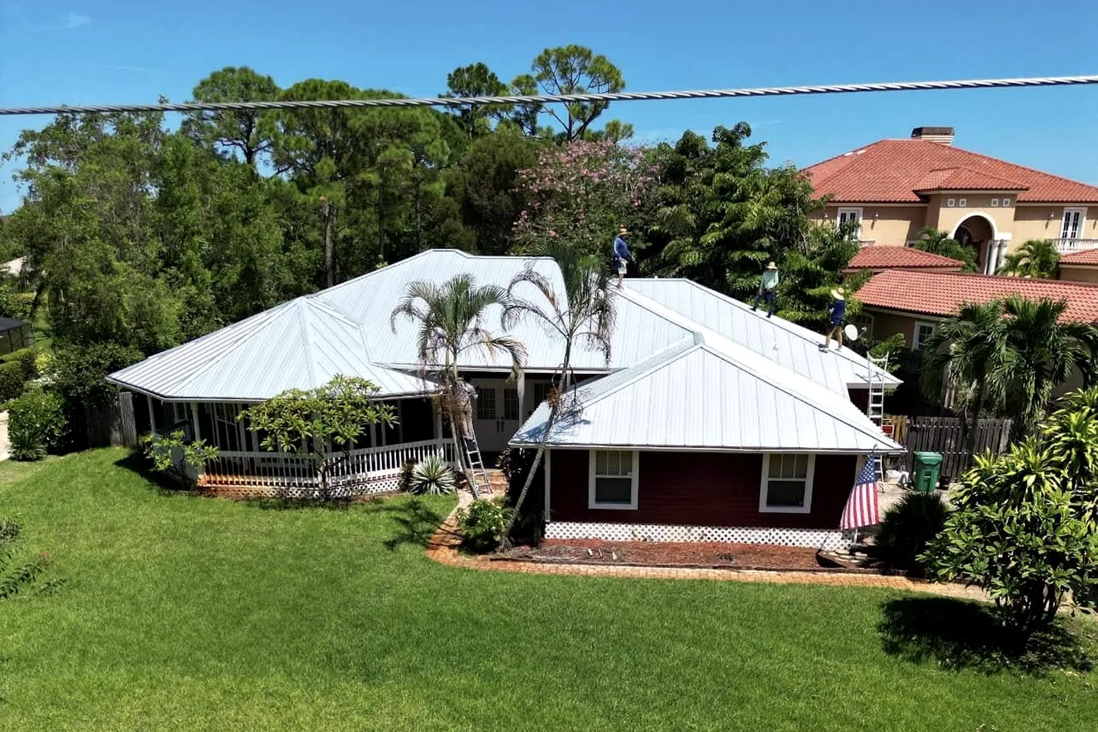 Aerial roof inspection view of metal roof with workers by Stormproof Roofing, Inc