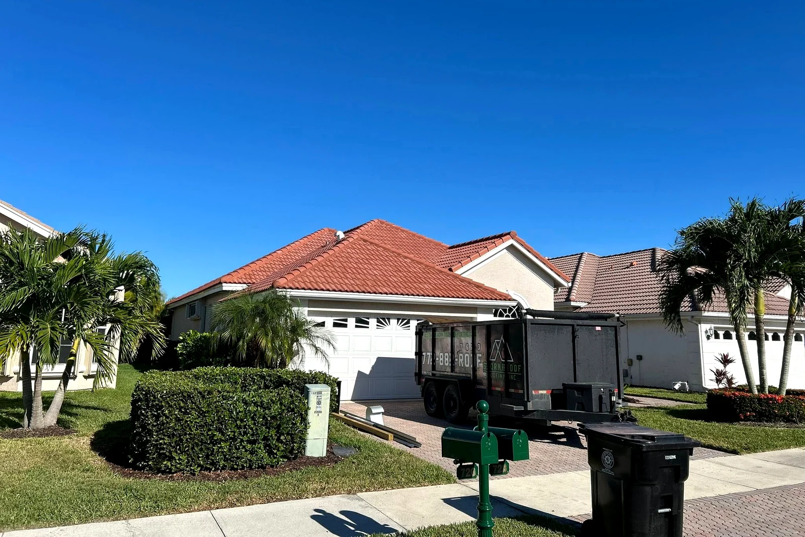 Red tile roof home with Stormproof Roofing jobsite trailer